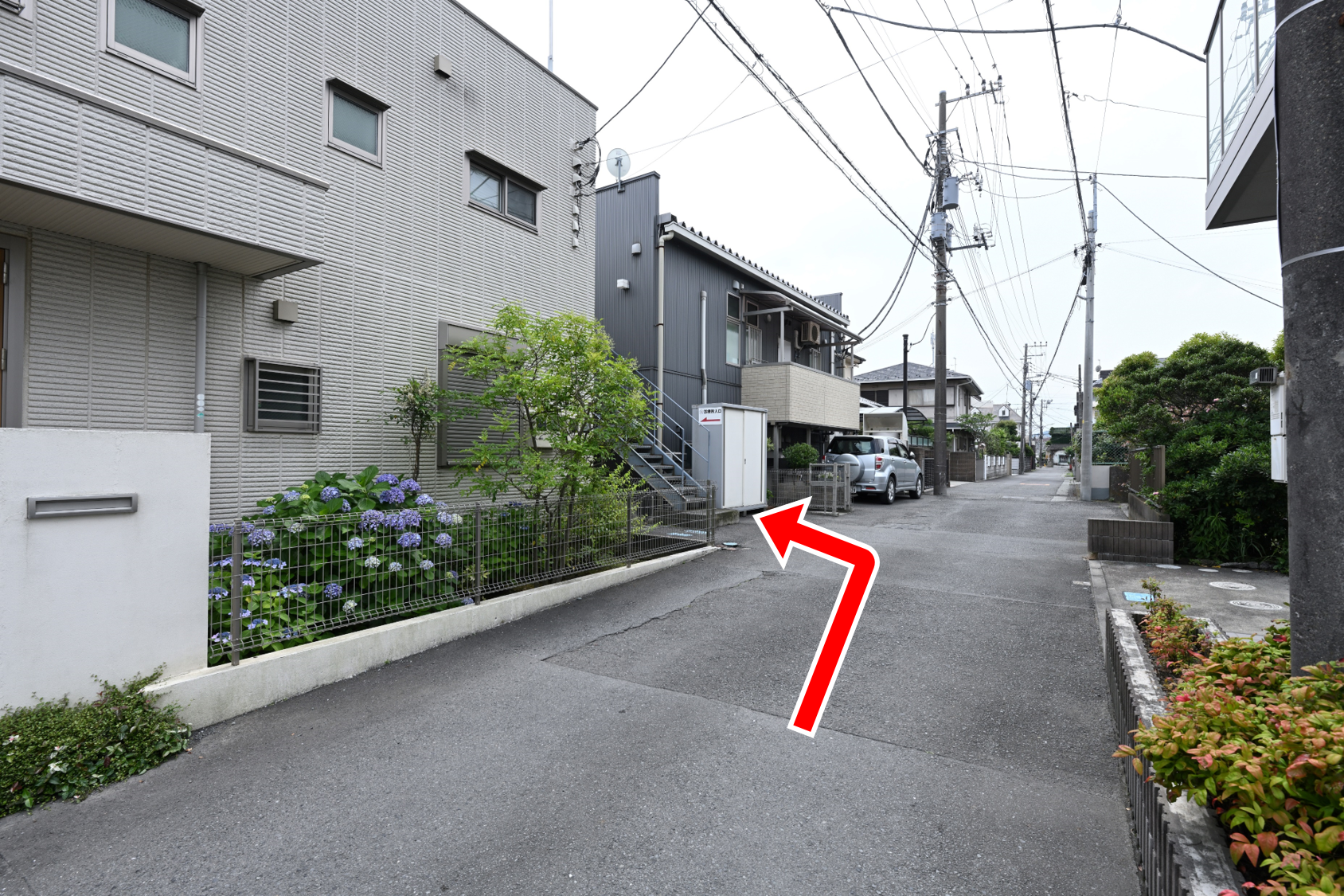 左手に階段のある建物が見えてきますので左折します